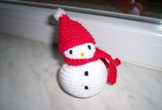 a small crocheted snowman sitting on top of a counter next to a window