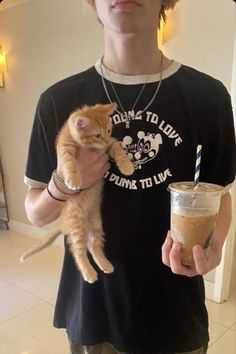 a person holding a drink and a cat