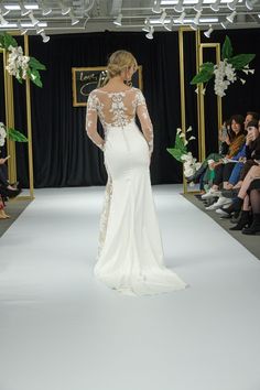 a woman in a wedding dress walking down the runway