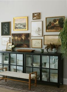 a living room with pictures on the wall and a bench in front of some glass doors