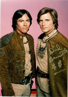 two men dressed in costumes with writing on them and one is wearing a brown jacket