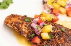 a piece of fish with pineapple salsa on it and some garnishes