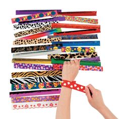 a person holding up a bunch of different colored bracelets in front of a white background