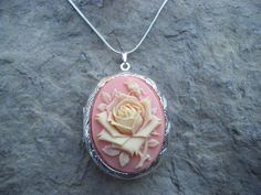 Beautiful cameo locket!!!  The cameo is a gorgeous creamy colored rose on a coral pink background!!!  The locket is victorian style with beautiful scroll on the front and back about 1 3/4" long.  It can hold two photos, keepsakes, or even your daily medication or vitamins!!! Pass down from generation to generation!!! The chain is 22"  1.2mm .925 plated snake chain with a lobster claw clasp!!! Perfect  for Brides or Bridal parties.  Makes a unique memorable gift for any occasion!!!  Timeless clas Pink Cameo Jewelry As A Gift, Pink Cameo Jewelry For Wedding, Pink Cameo Wedding Jewelry, Pink Cameo Necklace For Gifts, Vintage Peach Jewelry For Gifts, Cameo Locket, Background High Quality, Christmas Weddings, Bridal Parties