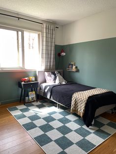 a bed room with a neatly made bed and a checkered rug