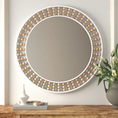 a round mirror sitting on top of a wooden dresser next to a potted plant