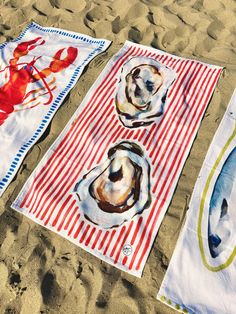 two beach towels with seashells on them laying in the sand