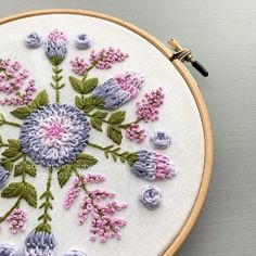 a close up of a embroidery on a hoop with pink and blue flowers in it