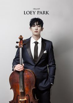 a man wearing a suit and tie holding a violin in front of a sign with the words loey park on it