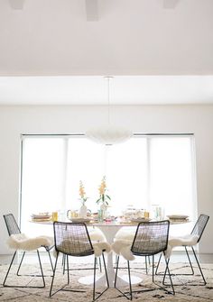 a dining room table with four chairs and a rug on the floor in front of it