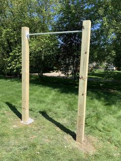 a wooden pole with two poles attached to it in the middle of a grassy field