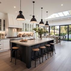 a large kitchen with an island and lots of lights hanging from the ceiling above it