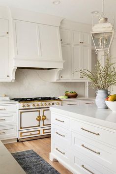 a kitchen with white cabinets and gold trim