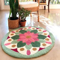 a green and pink rug sitting on top of a floor next to a potted plant