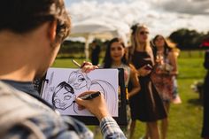 a group of people standing around each other in a field with a drawing on paper