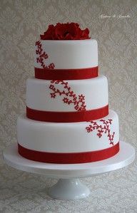 a three tiered cake with red flowers on top