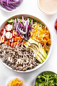 a white bowl filled with different types of salads and dressings on top of a table