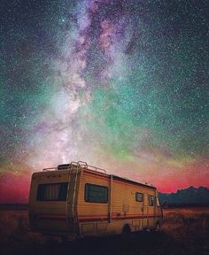 an rv parked in the middle of a field under a night sky filled with stars