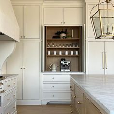 a kitchen with white cabinets and marble counter tops, gold pulls on the cupboards