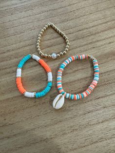 two bracelets on a wooden table one with shell and the other with beaded beads