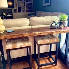 two stools sit at the end of a wooden table in front of a couch