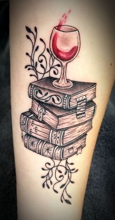 a tattoo with books and a wine glass on it