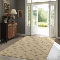 a living room with an open door and rug on the floor