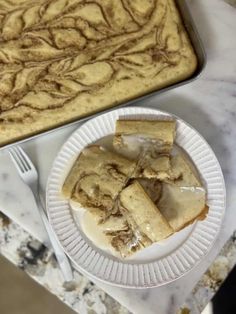 a white plate topped with slices of cake next to a baking pan filled with baked goods