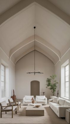 a living room filled with white furniture and large windows on the side of the wall