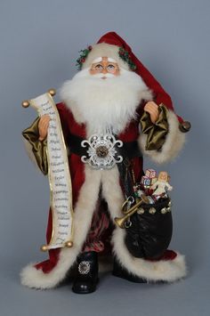 a santa clause figurine is holding a scroll and some other items in his hand