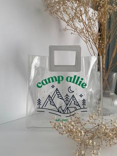 a clear bag sitting on top of a table next to a vase filled with flowers