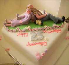 a birthday cake with two people laying on it