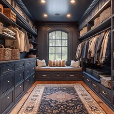 a large walk in closet with lots of clothes and rugs on the floor next to it