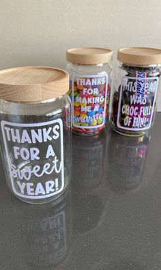 three glass jars with wooden lids and labels on them that say thanks for a great year