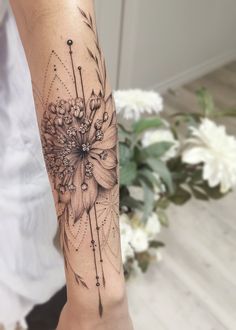 a woman's arm with a flower tattoo on it and an arrow in the middle