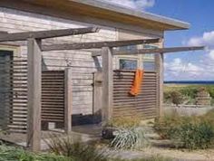 an old building with wooden shutters on the front and side, along with some plants