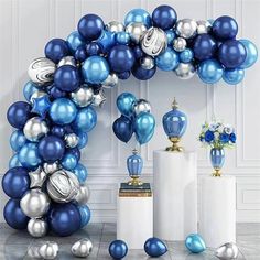 a blue and silver balloon arch with vases on the floor in front of it