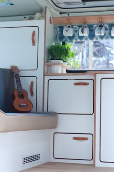 the interior of a camper with an instrument and potted plant on the shelf