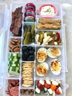 a plastic container filled with lots of different types of vegetables and meats next to crackers