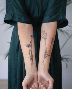 two women holding hands with tattoos on their arms and flowers tattooed on the arm, both of them