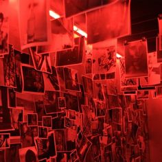 many pictures are hanging on the wall with red light coming from them and there is no image to describe