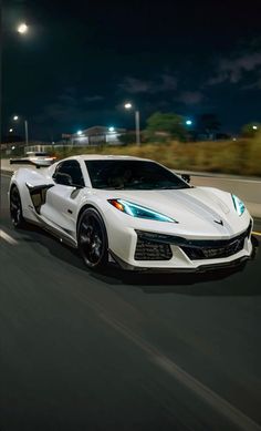 a white sports car driving down the road at night