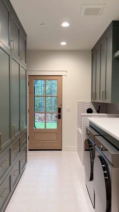 a kitchen with gray cabinets and white flooring, along with a washer and dryer