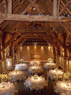 the inside of a barn with tables and chairs set up for a wedding reception in white linens