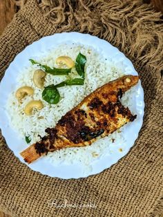 a white plate topped with rice and chicken next to cashews on a table