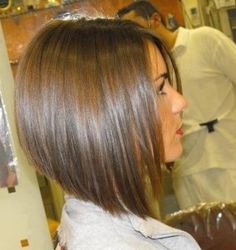 a woman sitting in a chair with her hair cut back and looking into the mirror