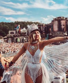 a woman in a white bodysuit and headpiece with wings on her shoulders at a music festival