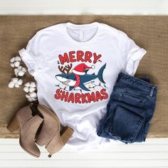 Make a splash this holiday season with our "Merry Sharkmas" Shark Santa Ugly Christmas T-shirt! This hilarious and festive tee features a jolly shark decked out in Santa gear, surrounded by twinkling Christmas lights. It's the perfect combination of fun and holiday cheer, ideal for ugly sweater parties, family gatherings, or just spreading some unique Christmas joy. Whether you're a fan of sharks, love quirky holiday designs, or just want to stand out in the crowd, this shirt is a must-have for Christmas Shark, Shark Graphic, Ugly Sweater Party, Christmas Gifts For Him, Christmas T Shirt, T Shirt Funny, Holiday Design, Unique Christmas, Funny Christmas