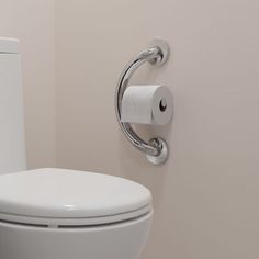 a white toilet sitting in a bathroom next to a roll of toilet paper