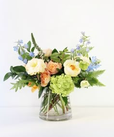 a vase filled with flowers and greenery on top of a table